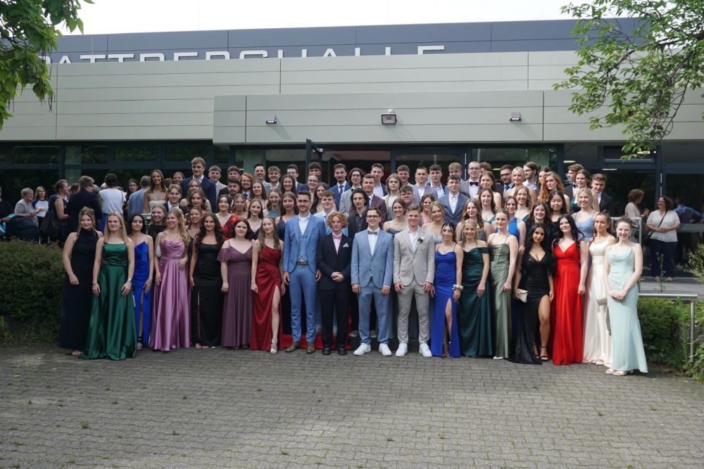 Abiturientinnen und Abiturienten in schicker Kleidung vor der Pattberghalle