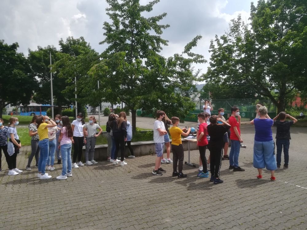 Schülerinnen und Schüler auf dem Pausenhof um die Sonnenfinsternis zu beobachten