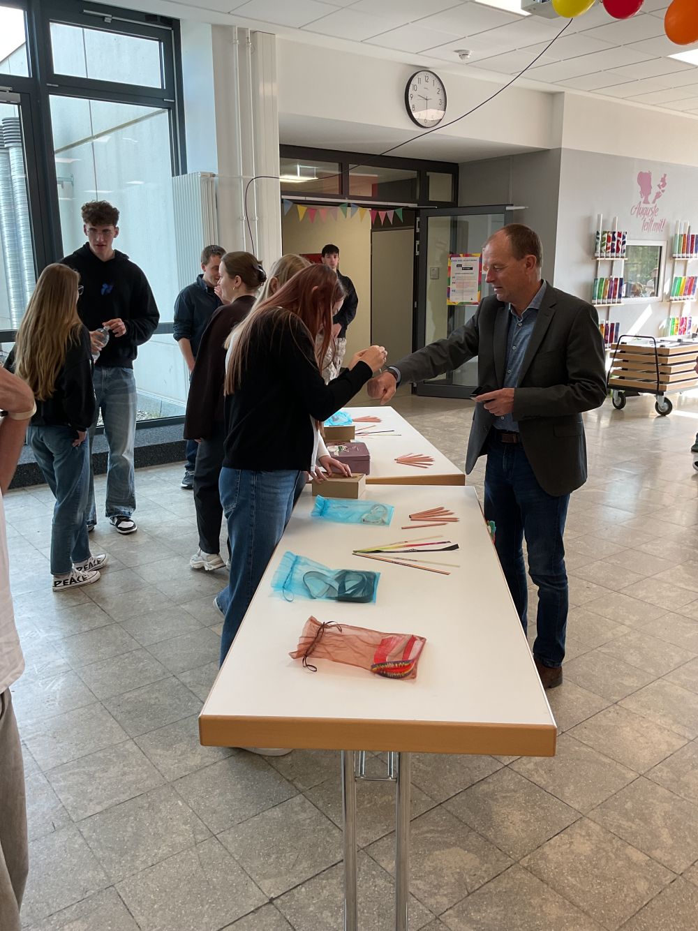 Schulleiter Dr. Pauer erhält ein Bändchen um das Handgelenk.